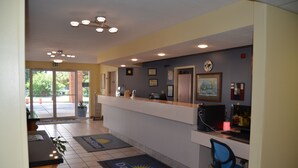 A reception area with a counter, computer, and seating. There are exit signs and a door leading outside.