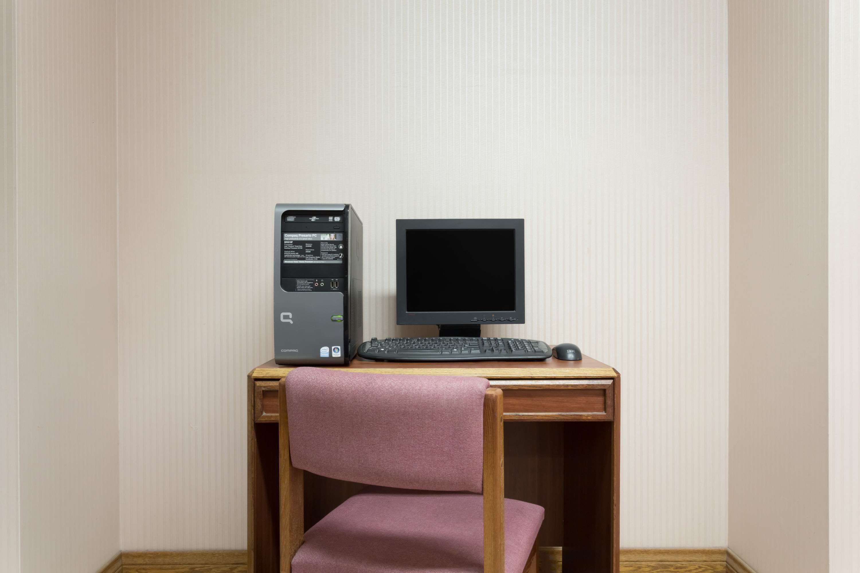 A wooden desk with a computer setup including a monitor, keyboard, and mouse.