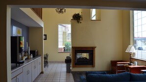 A living room with a blue sofa, a fireplace, and a kitchen area with cabinets and a countertop.