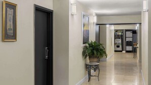 Ein Flur mit einer schwarzen Tür, einem Blumentopf und einem Kühlschrank im Hintergrund.