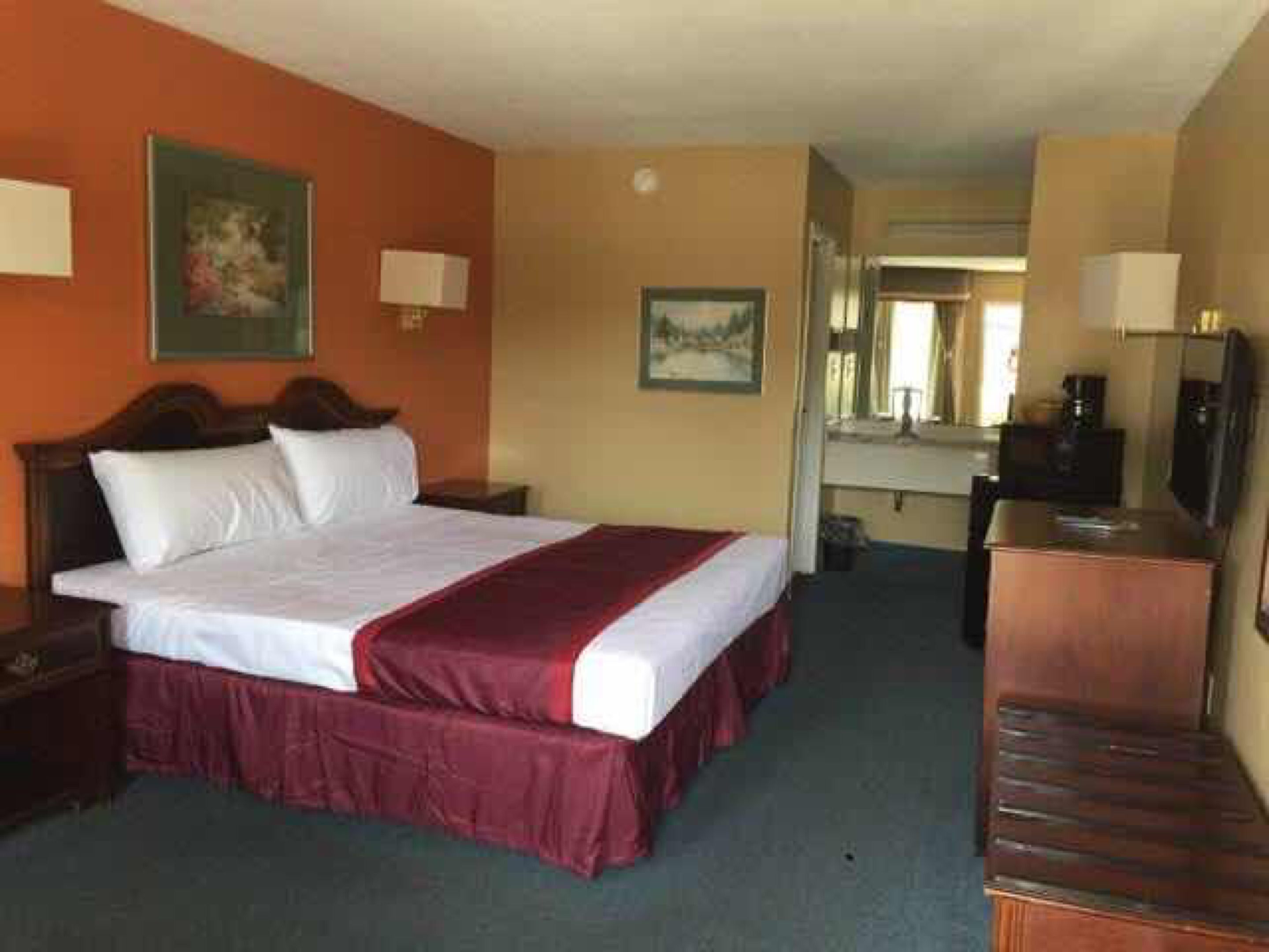 A hotel room with a bed, a desk, a chair, and a television.