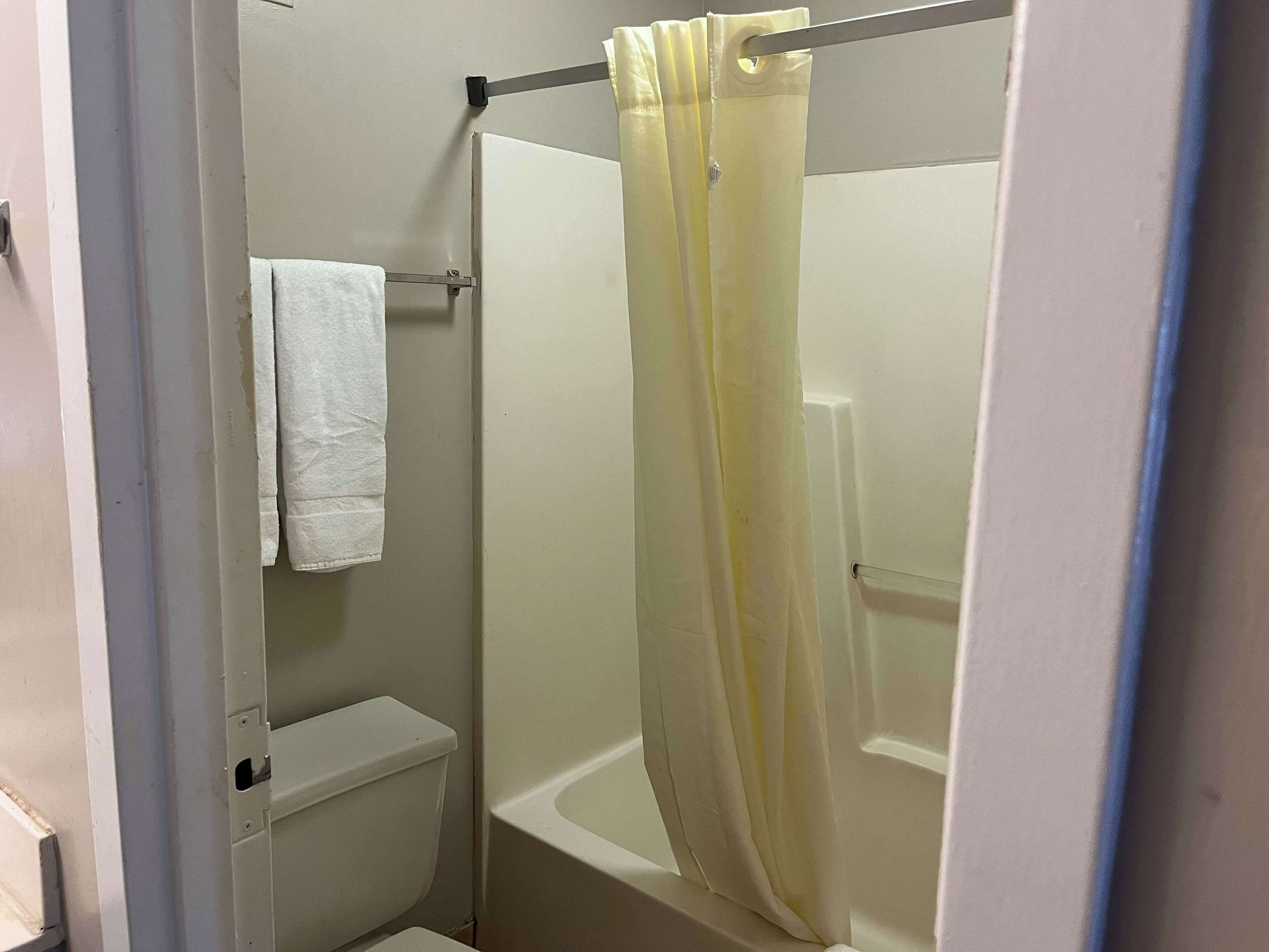 Een badkamer met een toilet, een douchegordijn en een handdoek aan de muur.