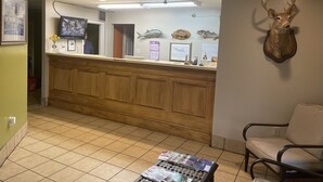 A reception area with a wooden counter, a mounted deer head, and a chair. - Motel 6 Bracey, VA – I-85 (Bracey)