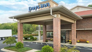 A Days Inn with a covered entrance, brick pillars, and a parking lot with a white truck.