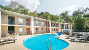 A pool area with lounge chairs and a building with multiple balconies.
