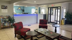 A reception area with a blue counter, two red armchairs, and a glass-top table. - Days Inn by Wyndham Centerville (Centerville)