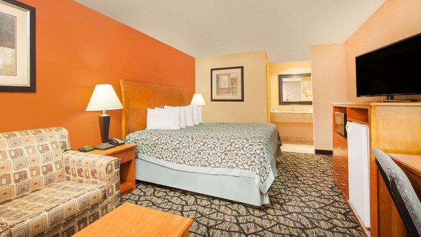 A hotel room with a bed, a sofa, a desk, a television, and a bathroom. - Days Inn by Wyndham Centerville (Centerville)