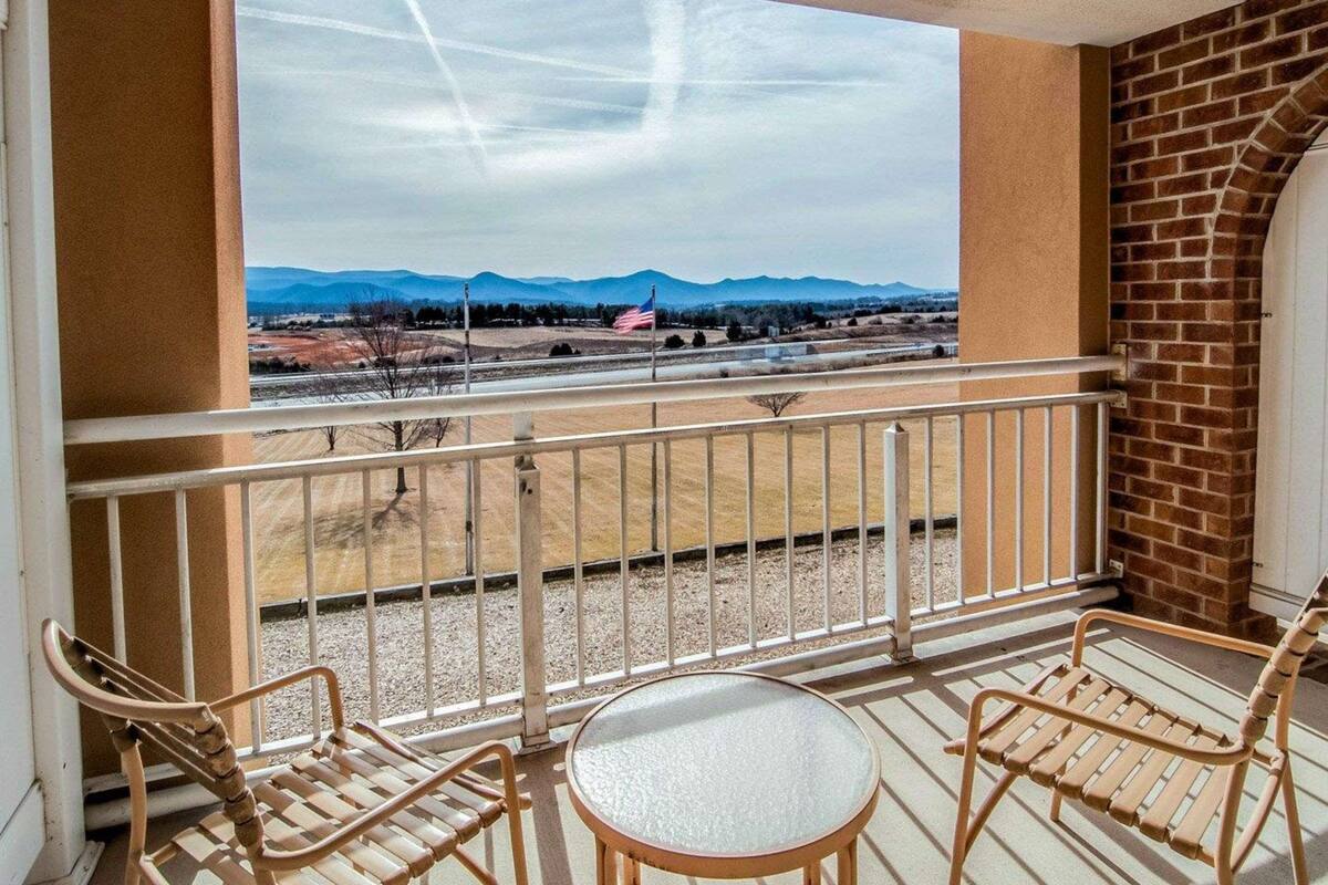 Un balcon avec vue sur les montagnes, une table et deux chaises.