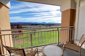 A balcony with a view of a grassy field and mountains, furnished with two chairs and a table. - Comfort Inn & Suites Raphine - Lexington near I-81 and I-64 (Raphine)