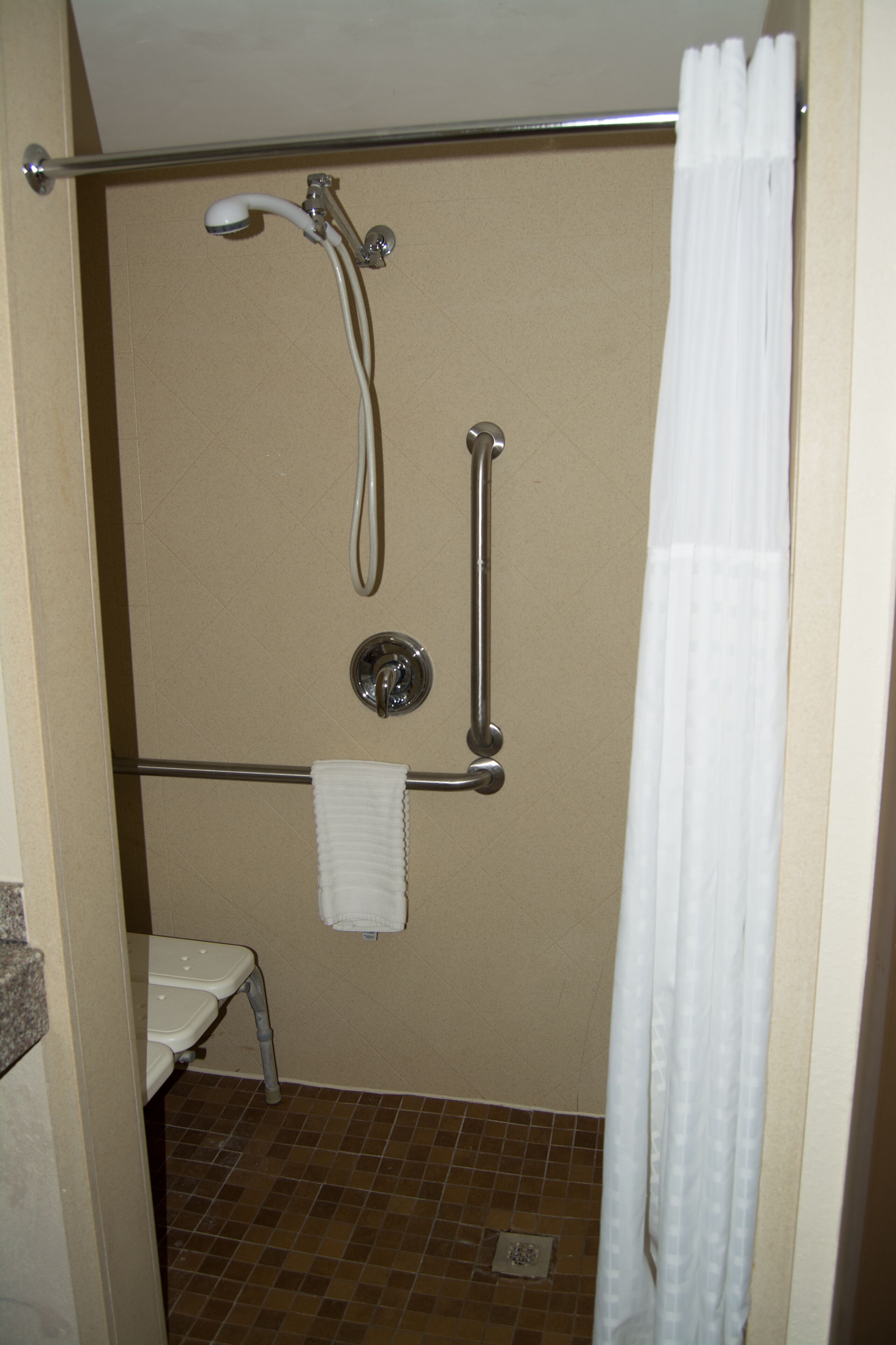 Une salle de bain équipée d’une douche, d’une barre d’appui et d’un porte-serviettes.