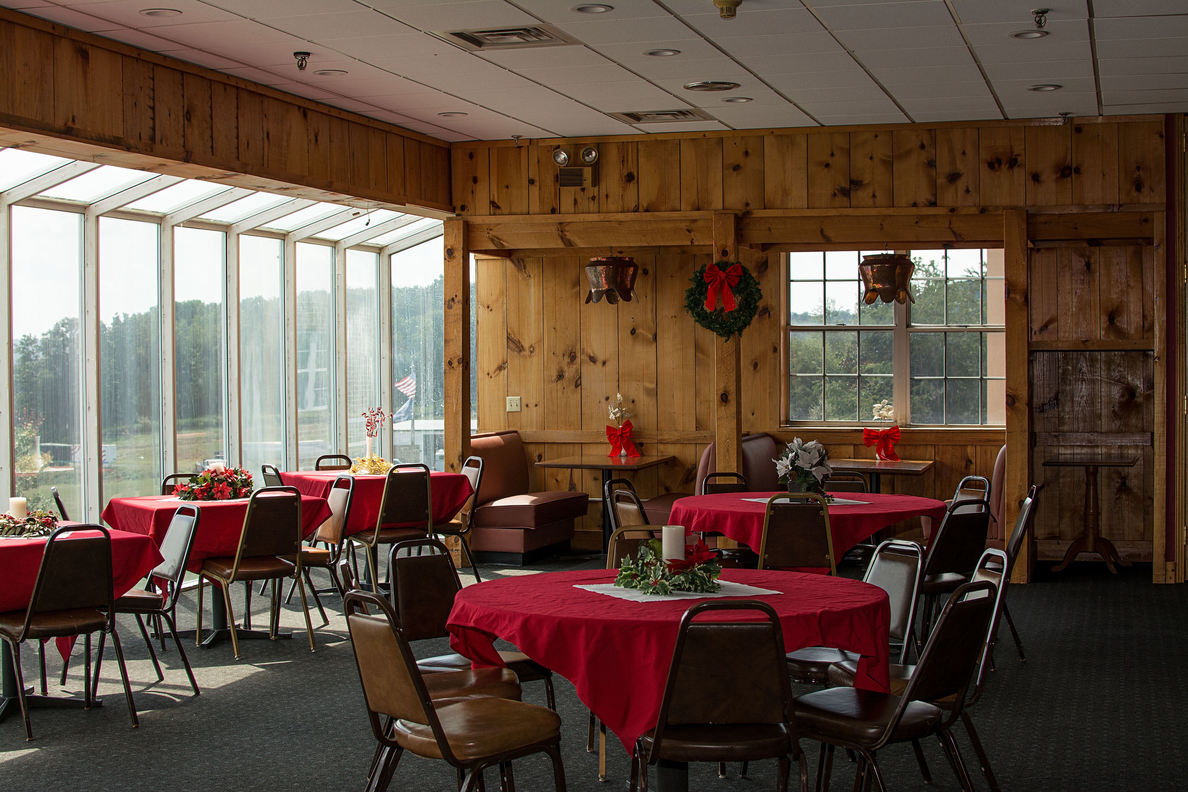 A dining area with tables set for a meal, wooden walls, and large windows.
