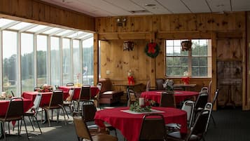 A dining area with tables set for a meal, wooden walls, and large windows.
