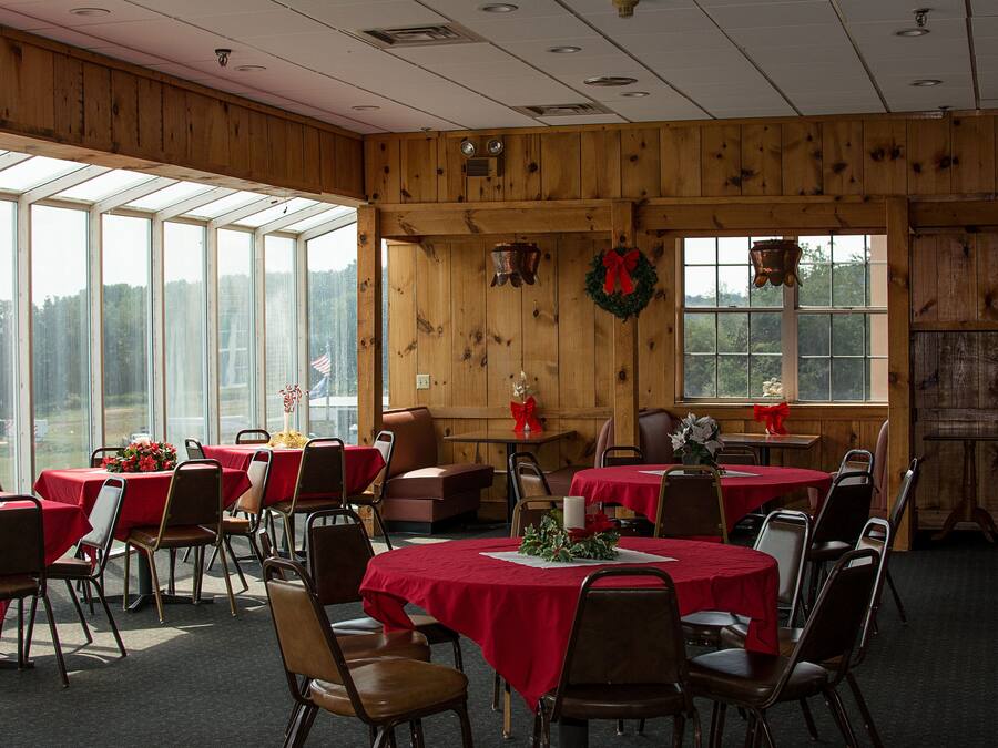 A dining area with tables set for a meal, wooden walls, and large windows.