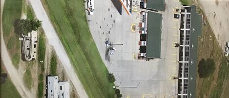 An aerial view of a parking lot with RVs and cars, a Shell gas station, and a building with a green roof.