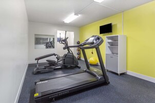 Un gimnasio con cintas de correr, elípticas y bicicletas estáticas.