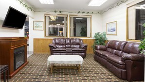 A living room with a brown leather sofa, a wooden coffee table, and a flat-screen TV mounted on the wall. - Days Inn by Wyndham Paxton (Paxton)