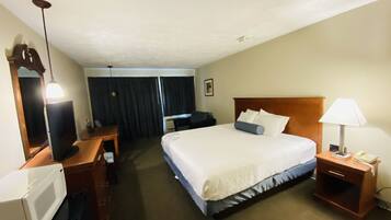 Una habitación de hotel con cama, escritorio, ordenador, lámpara y teléfono.
