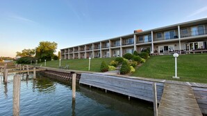 A multi-story hotel with a pool area, a dock, and a well-maintained lawn.