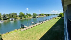 A waterfront property with a dock, grassy areas, and a clear view of the water.