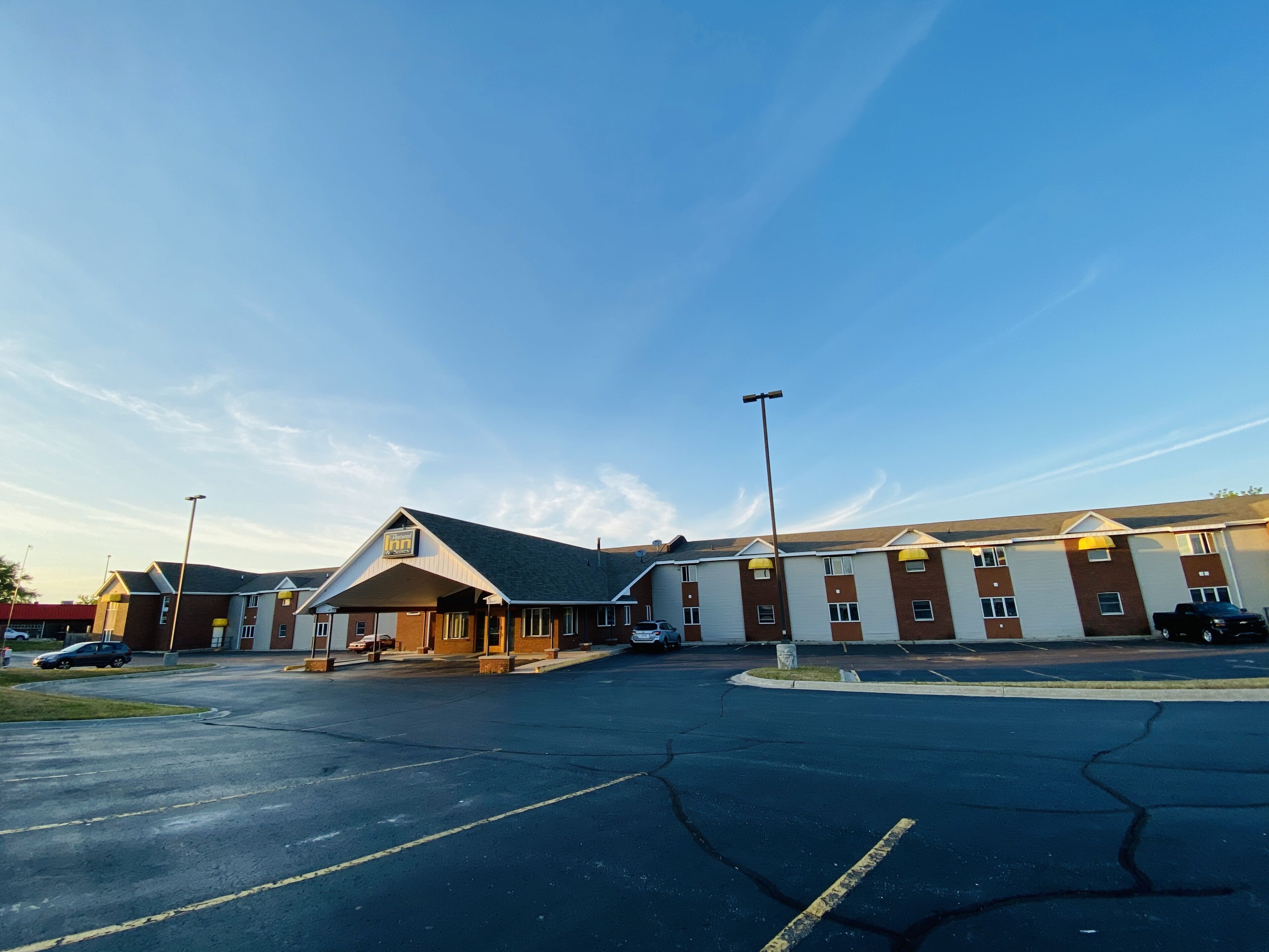 A parking lot with a building featuring a prominent entrance and a large sign.