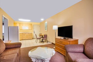 Un espacio habitable compacto con kitchenette, comedor, sofá, televisor y lámpara.