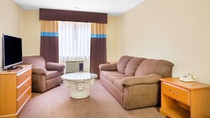 Een hotelkamer met een bank, een salontafel, een televisie, een dressoir en een telefoon.