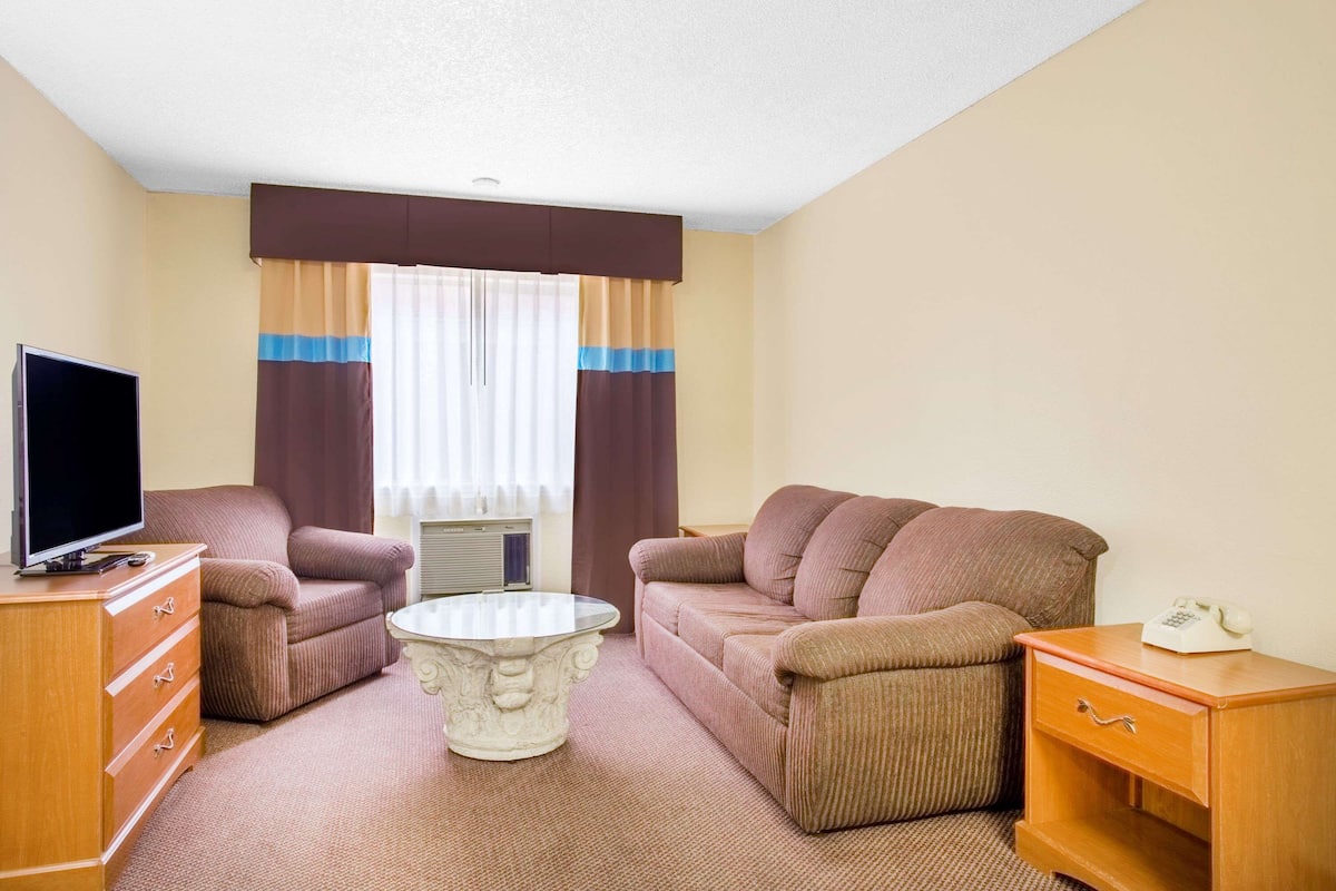 A hotel room with a sofa, a coffee table, a TV, a dresser, and a telephone.