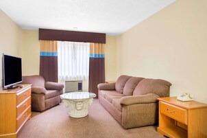 Una habitación de hotel con sofá, mesa de centro, televisor, cómoda y teléfono.