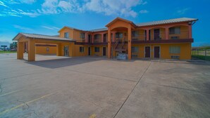 A multi-story hotel with a central courtyard, balconies, and a clear sky. - Texas Inn San Benito near Harlingen (San Benito)