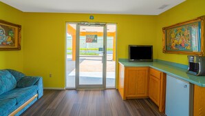 A room with a sofa, a television, a coffee maker, and a door leading outside. - Texas Inn San Benito near Harlingen (San Benito)