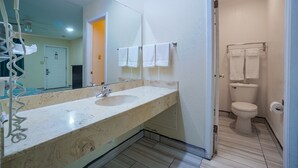 A bathroom with a sink, mirror, and toilet. - Texas Inn San Benito near Harlingen (San Benito)