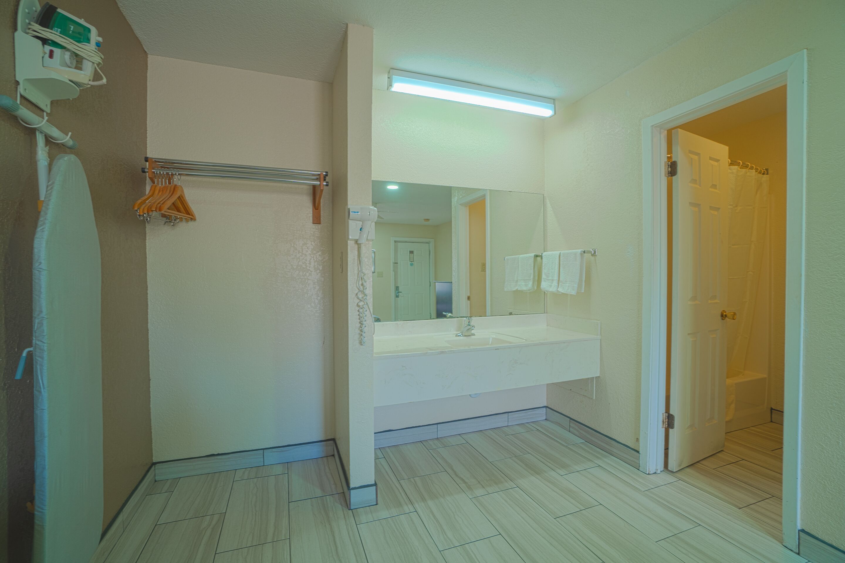 A bathroom with a large mirror, white sink, and a shower area.