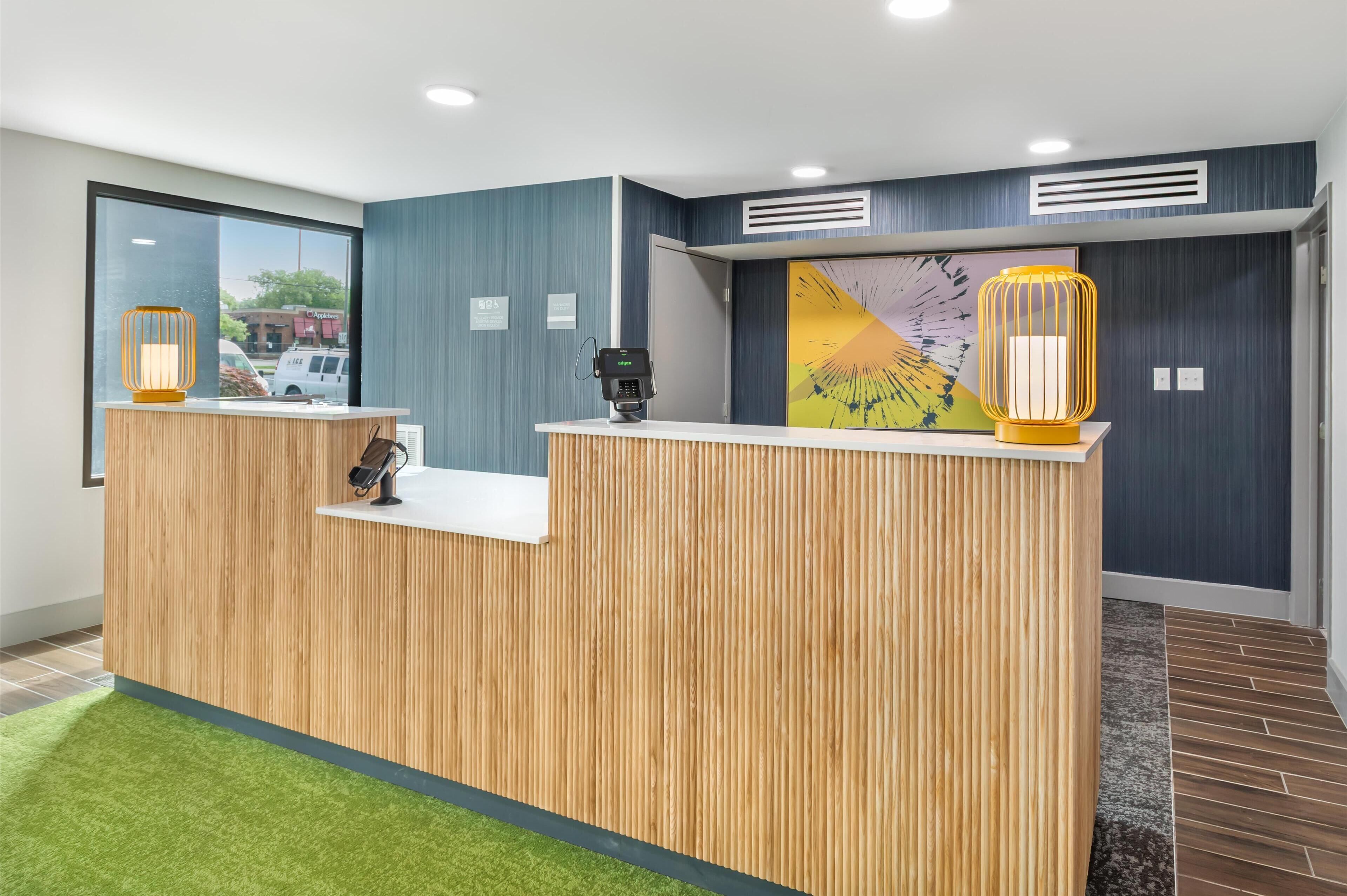 A reception desk with a wooden finish, a digital payment terminal, and two decorative lamps.