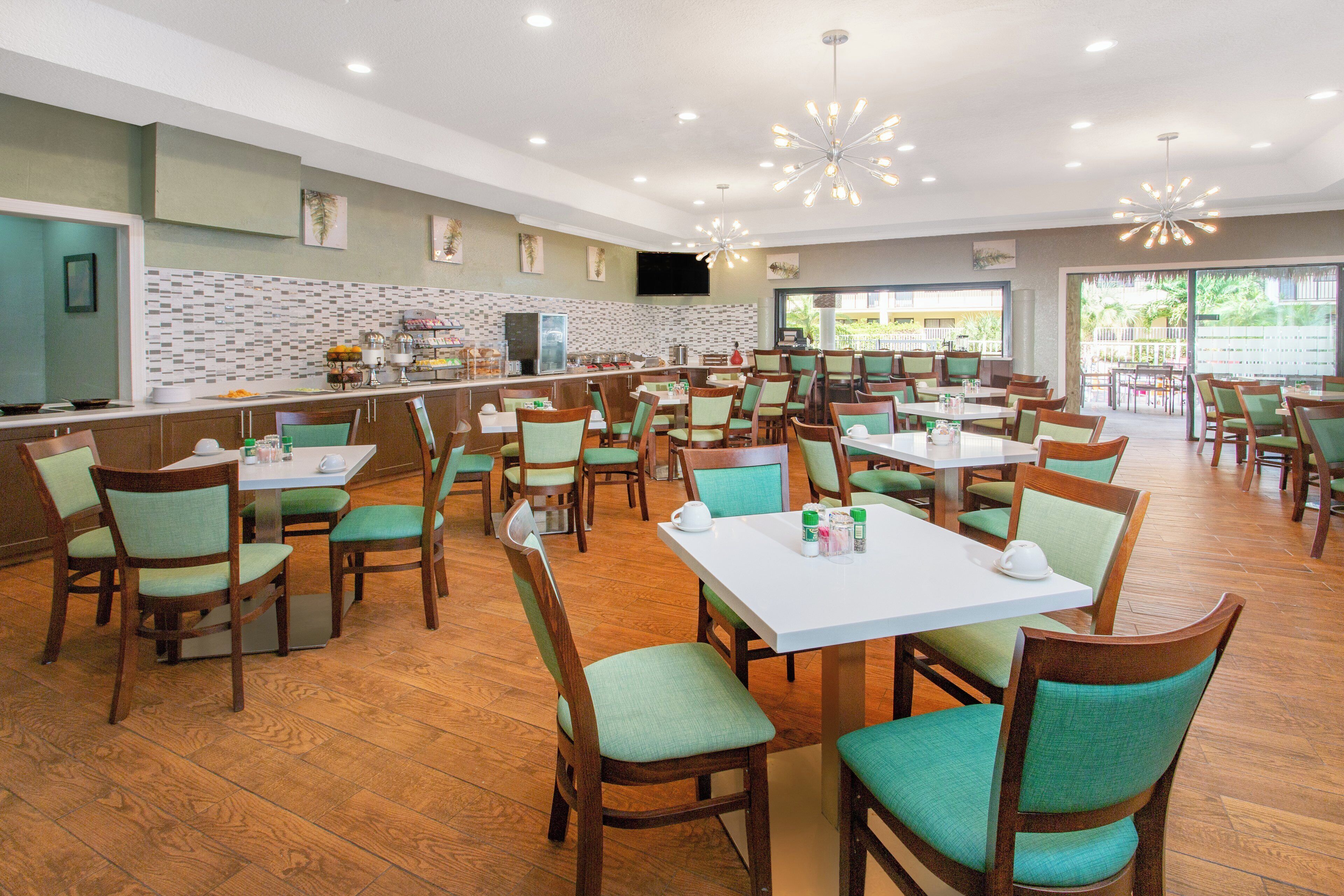 A spacious dining area with multiple tables and chairs, a buffet counter, and a television mounted on the wall.