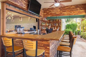 A bar area with a wooden counter, bar stools, and a bartender.
