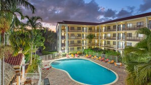 Un hôtel doté d’une piscine, d’un espace extérieur aménagé et de palmiers.