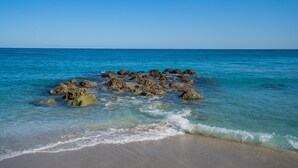 A beach with clear blue water and rocky formations near the shore. - Holiday Inn & Suites Boca Raton - North by IHG (Boca Raton)