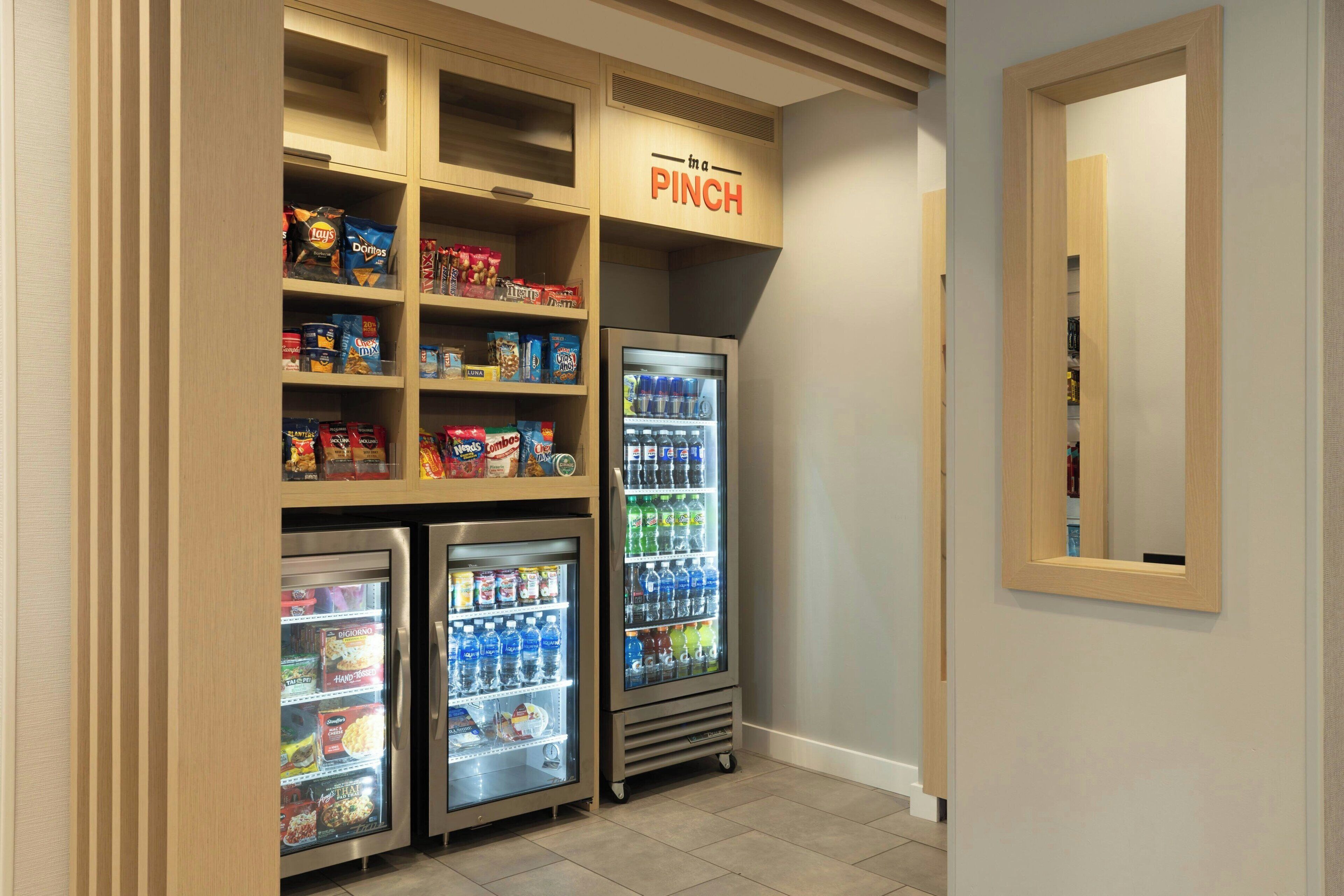 Een automaatruimte voor snacks en drankjes, met meerdere planken en vriezers, waaronder Doritos en andere lekkernijen.