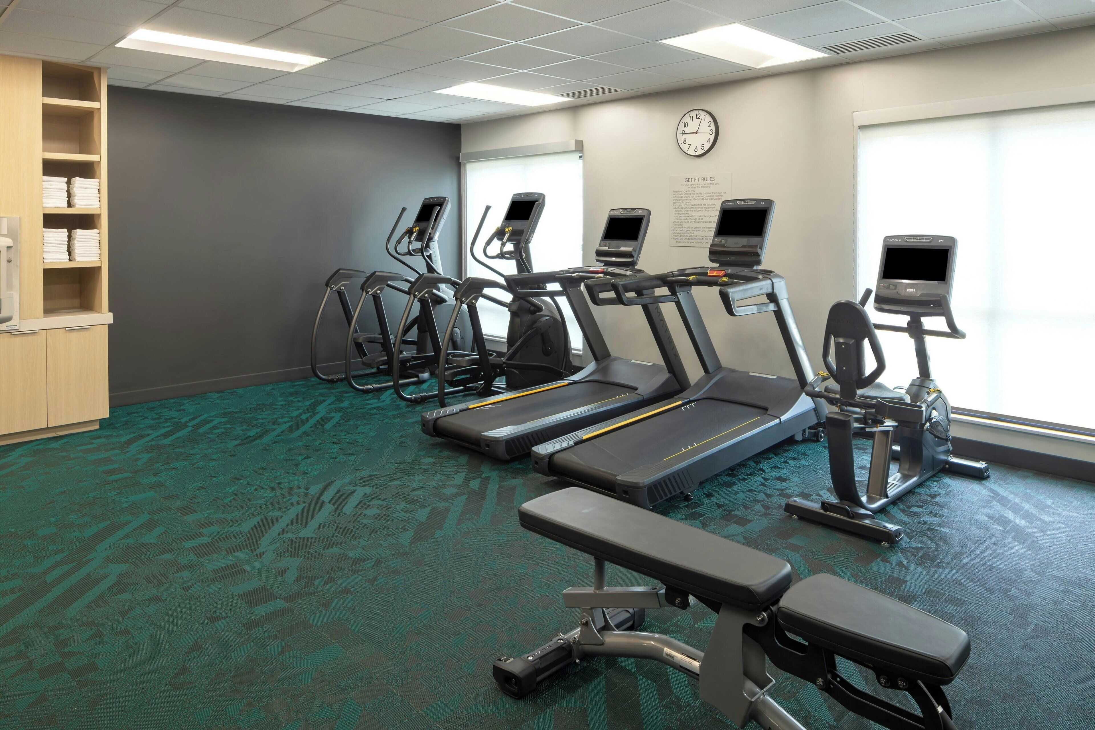 A gym with treadmills, elliptical machines, and a bench.