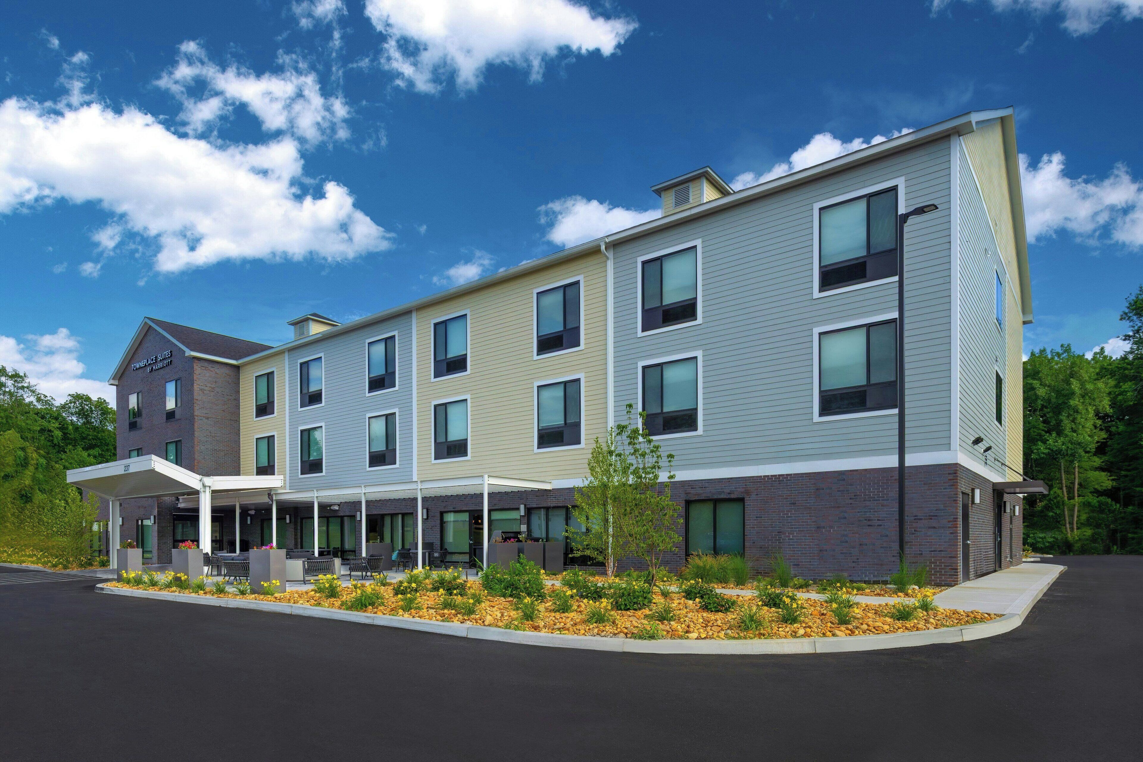 A multi-story hotel with a covered outdoor seating area and a landscaped garden.