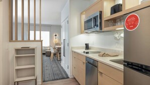 Eine moderne Küche mit integriertem Mikrowellenherd, Edelstahlkühlschrank und einem Holzschrank über der Spüle.