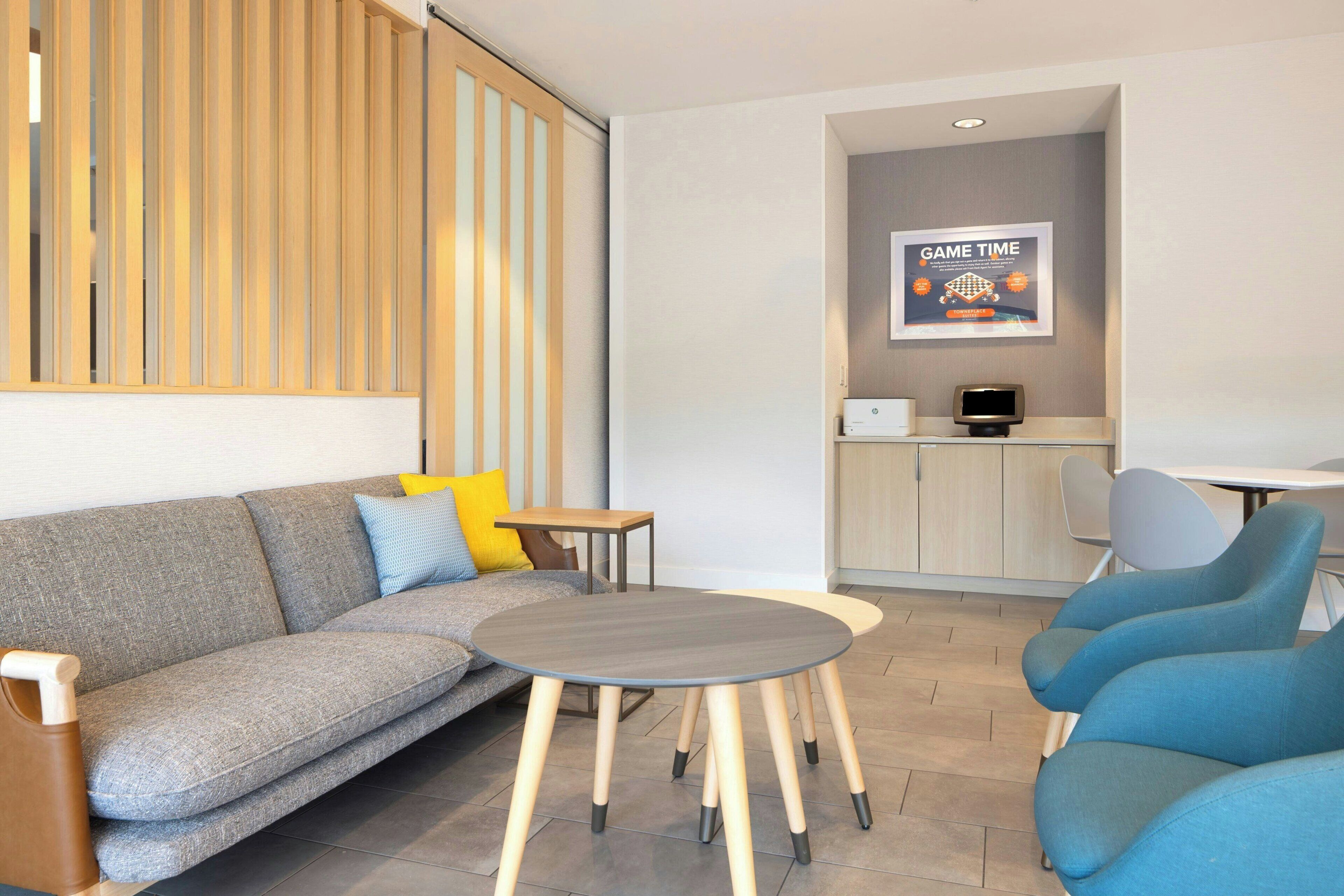 Una habitación de hotel moderna con un sofá, una mesita redonda y un área de descanso con sillas.