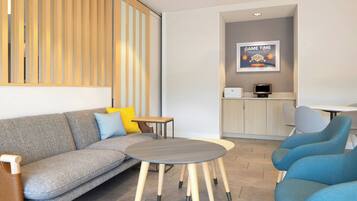 Una habitación de hotel moderna con un sofá, una mesita redonda y un área de descanso con sillas.