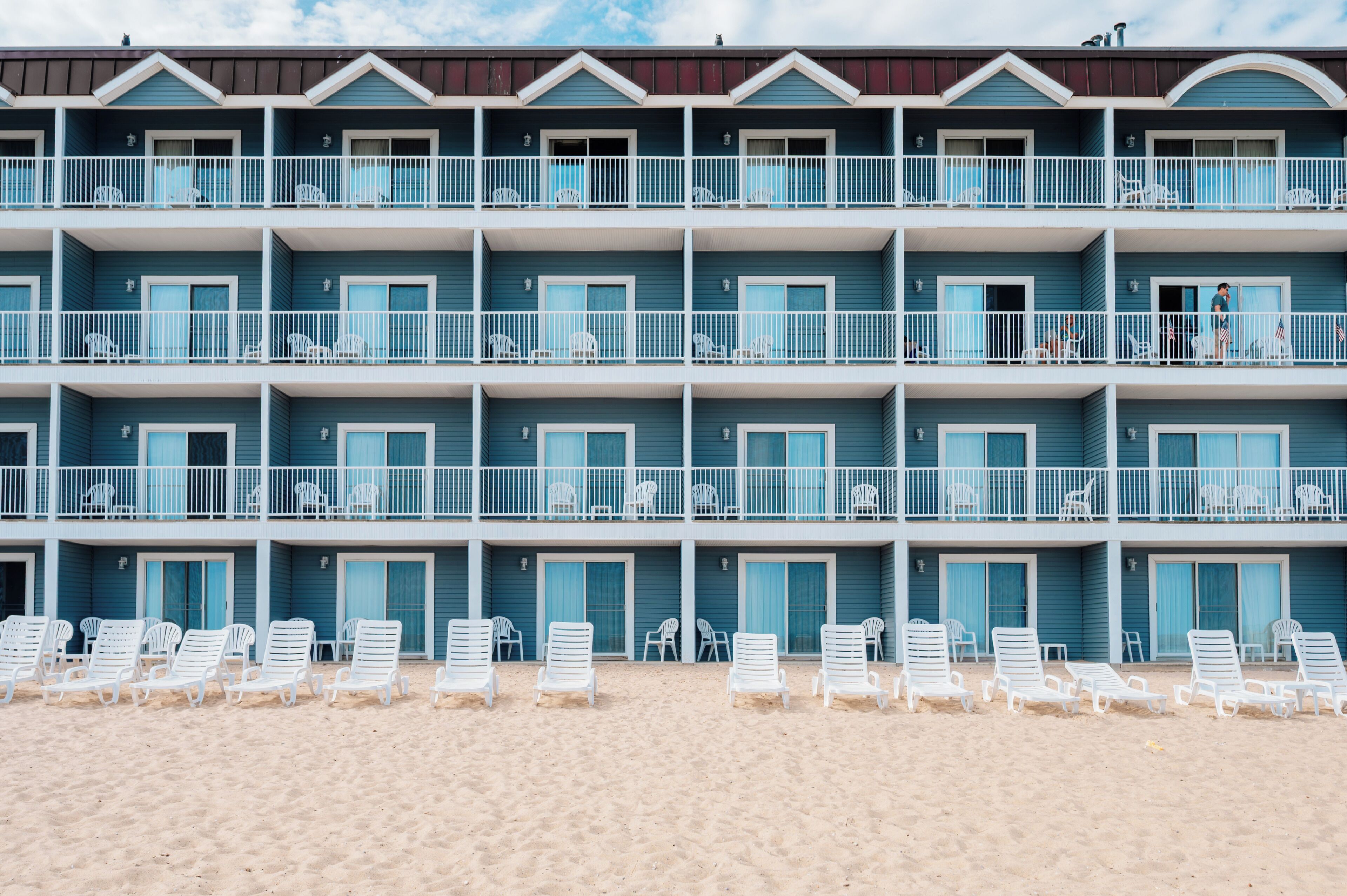 Un hotel de varios pisos con balcones, sillas de playa y una playa arenosa.