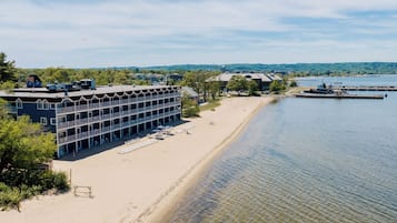 A waterfront hotel with a pool, beach chairs, and a dock.