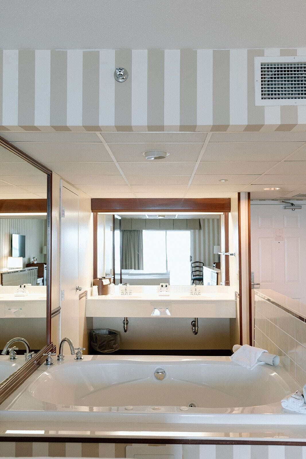 Un baño de hotel con una bañera grande, dos lavabos y un espejo sobre los lavabos.
