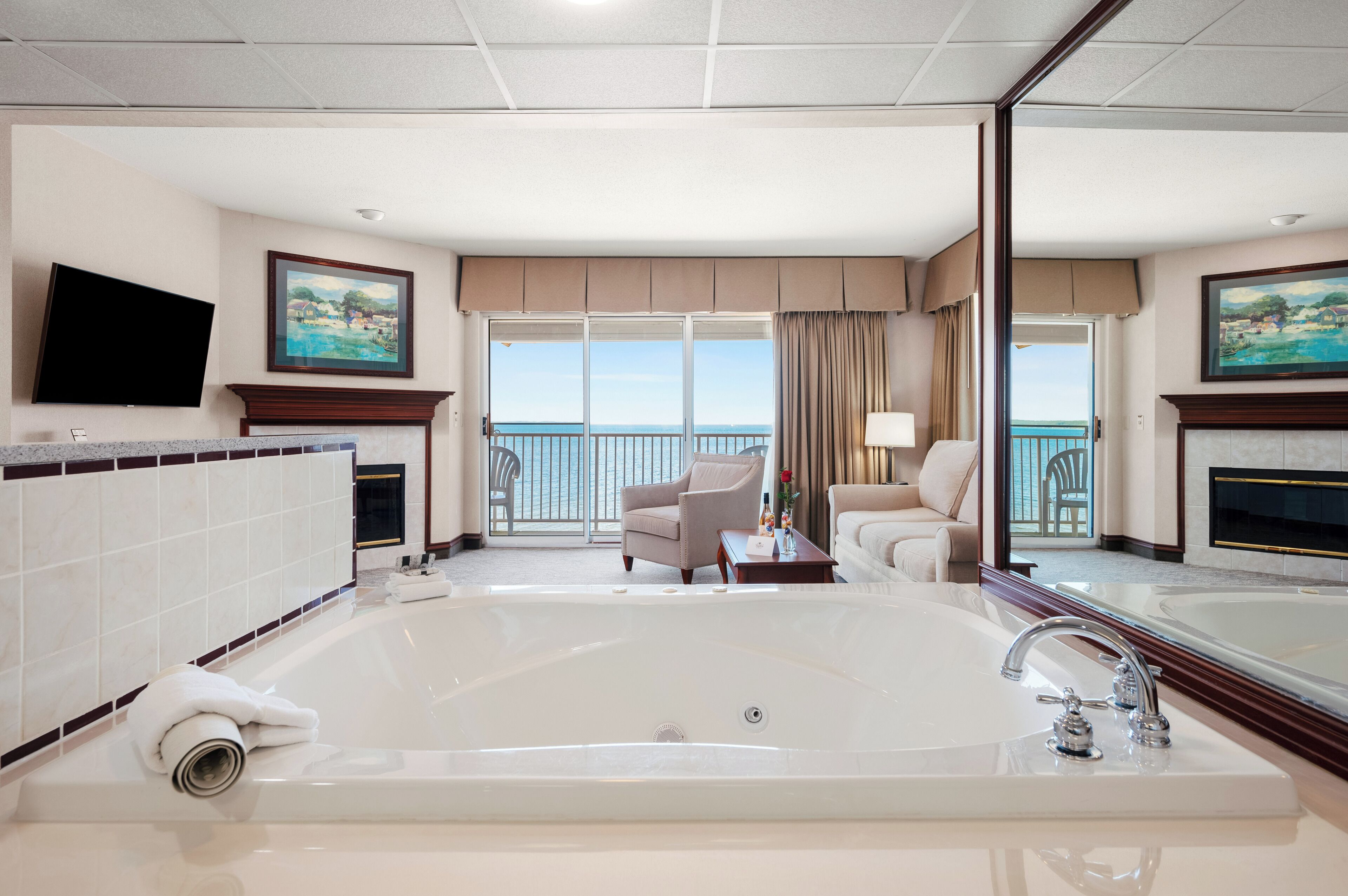 A spacious room with a large bathtub, a television, and a balcony with a view.