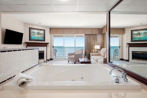 A spacious room with a large bathtub, a television, and a balcony with a view.