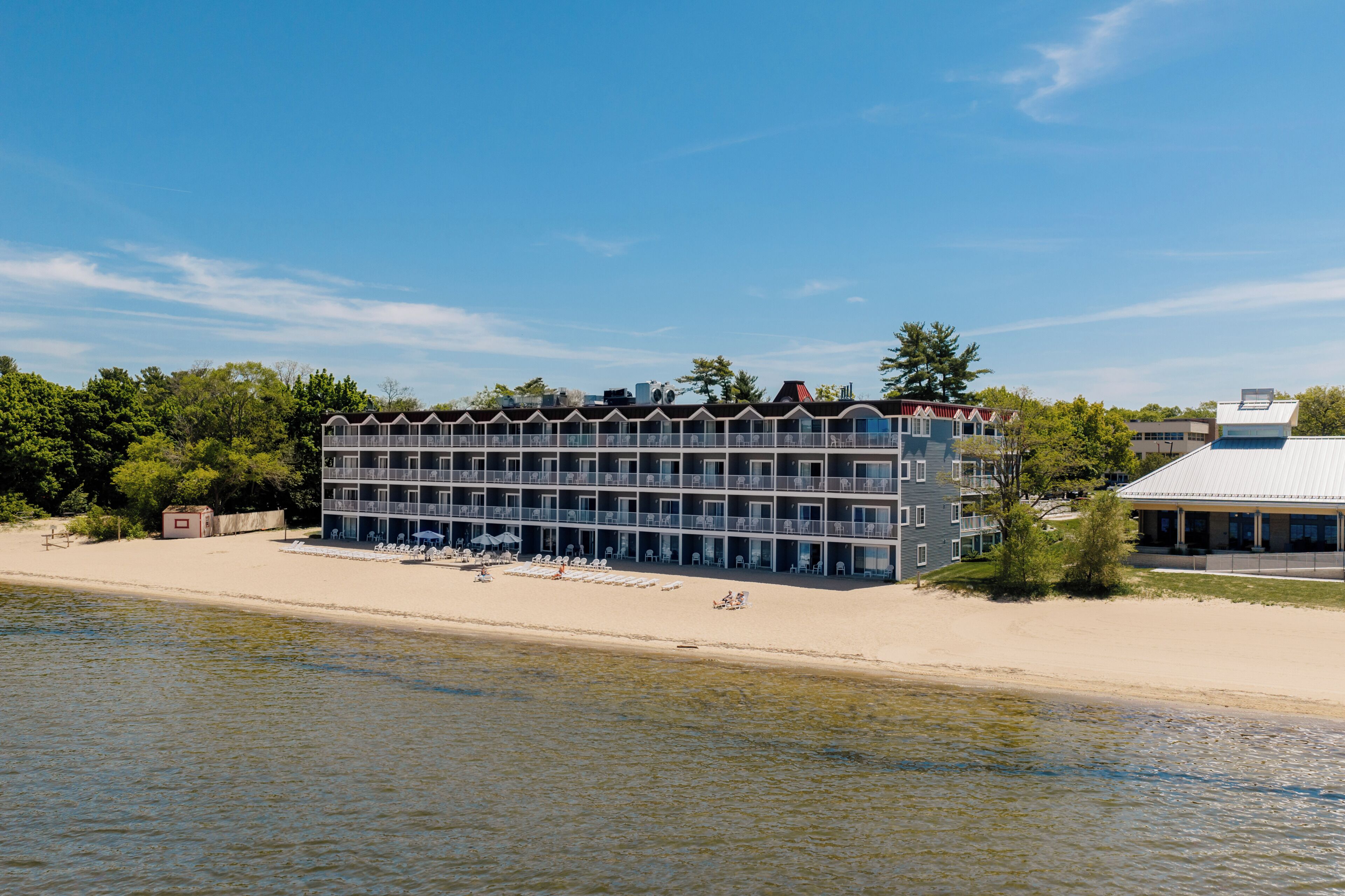 Un hôtel à plusieurs étages doté de balcons, situé sur une plage avec vue sur la mer.