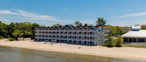 Un hôtel à plusieurs étages doté de balcons, situé sur une plage avec vue sur la mer.